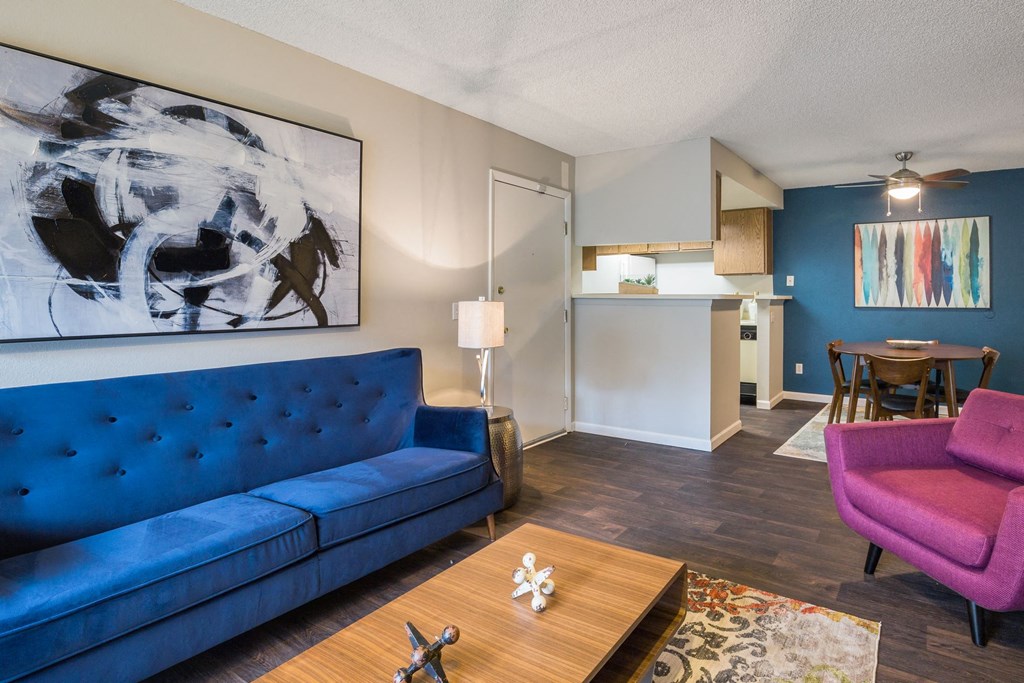 a living room and kitchen with a blue couch and a table