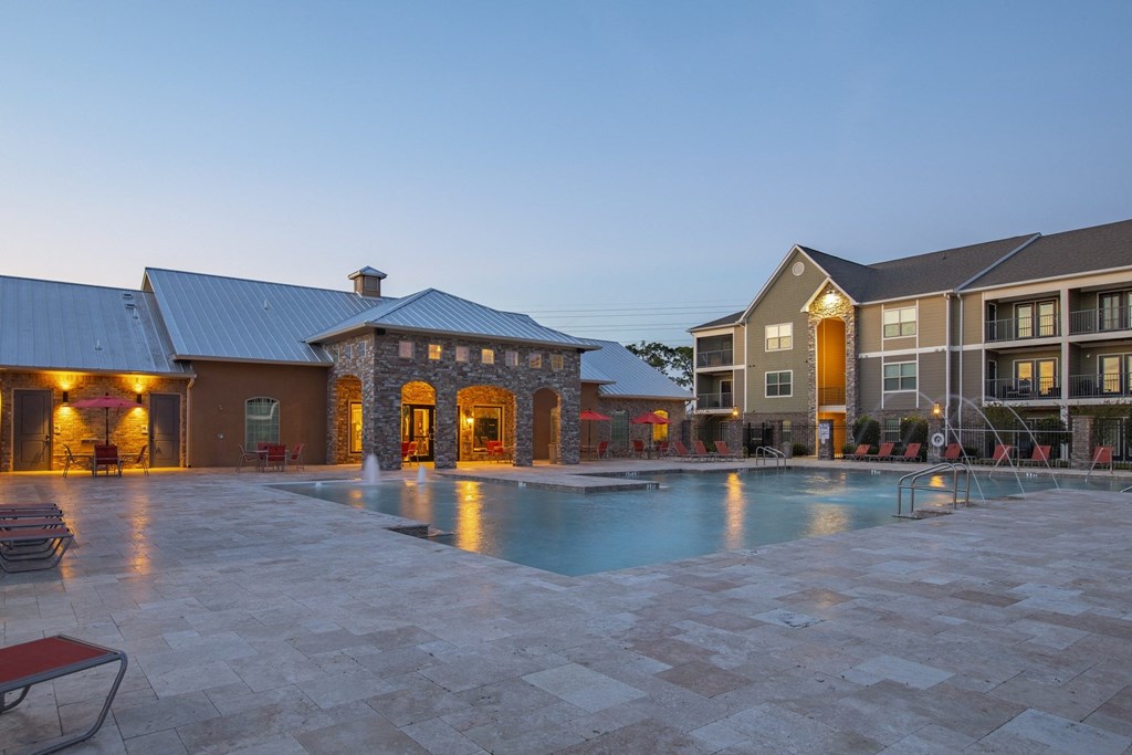 a swimming pool with an apartment building in the evening