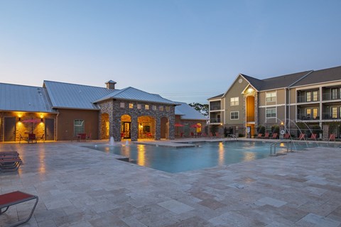 a swimming pool with an apartment building in the evening