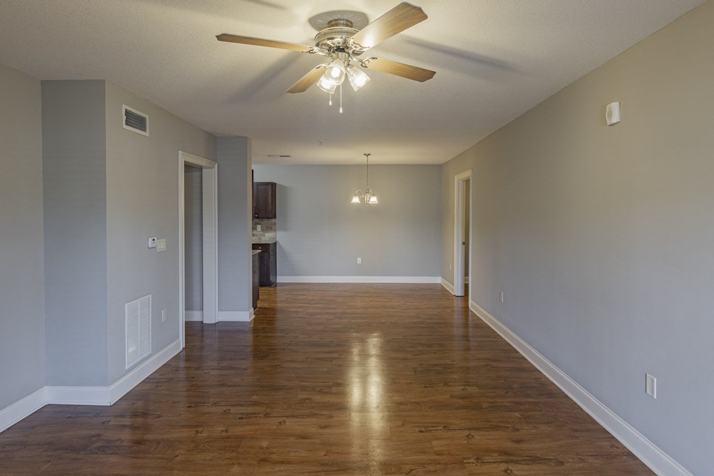 an empty living room with wood floors and a ceiling fan