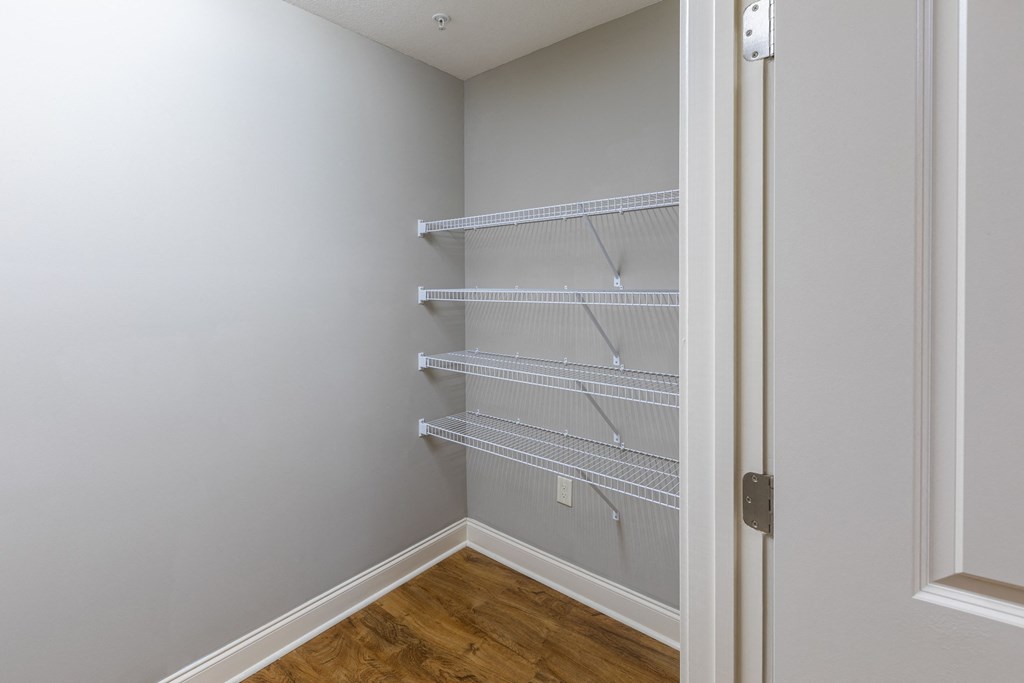an empty closet in a home with white walls and a wood floor