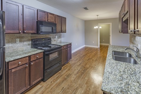 a kitchen with wood cabinets and granite counter tops and black appliances