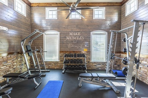 a gym with weights and exercise equipment in a building with wooden walls