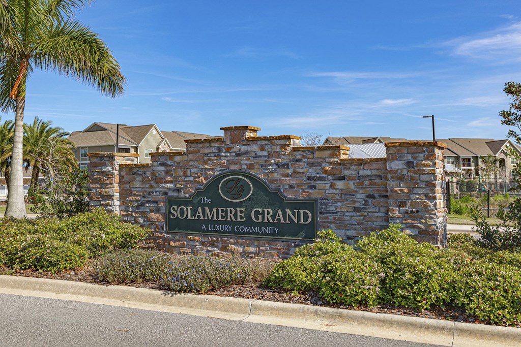 the solaire grand sign in front of a stone wall with palm trees