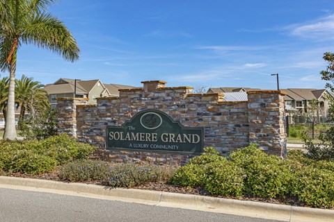 the solaire grand sign in front of a stone wall with palm trees
