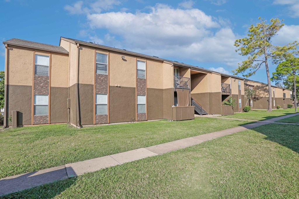 Our apartment buildings with a walkway in front and blue skies at Stone Canyon apartments in Shreveport, LA.