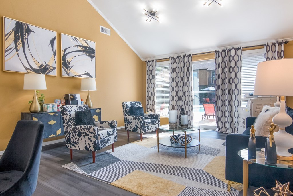 Lounge space in leasing office with black and white furniture and a large painting on the wall and a view to the pool at Stone Canyon apartments in Shreveport, LA.