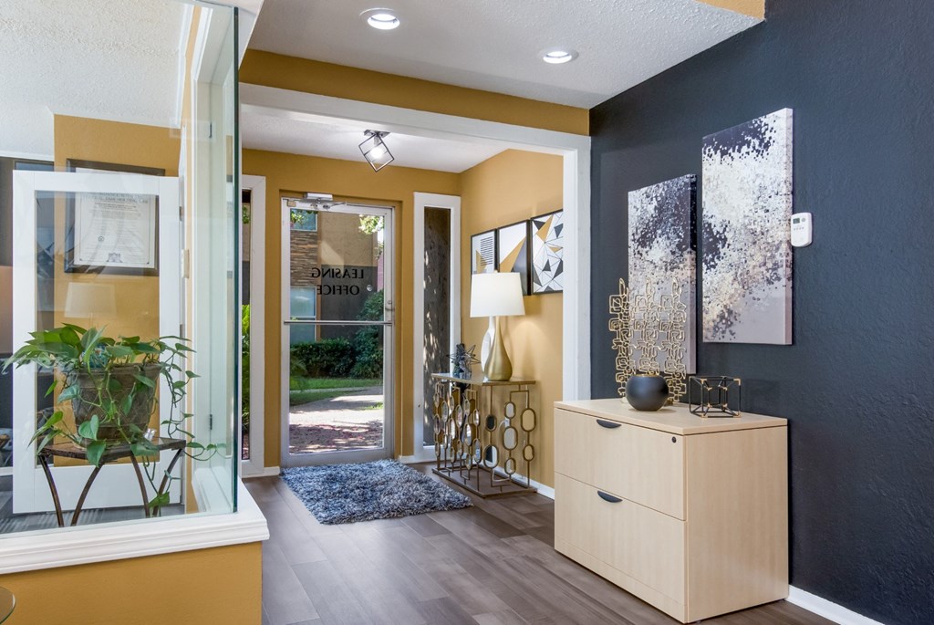 Entrance to leasing office with a wooden cabinet and a plant on a stand. at Stone Canyon apartments in Shreveport, LA.