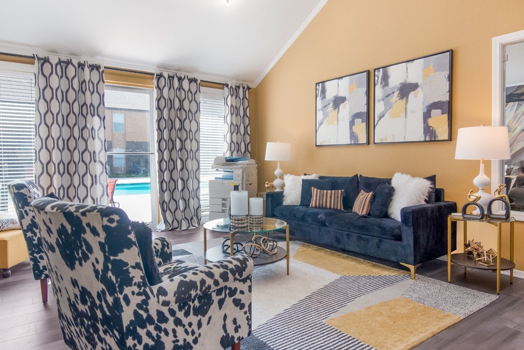 Lounge area in leasing office with a black and white patterned chair, a blue sofa and view of the pool at Stone Canyon apartments in Shreveport, LA.