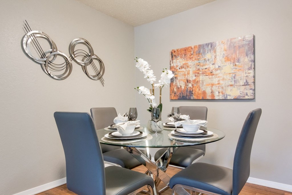 A dining table with four chairs and a vase of white flowers in the model apartment at Stone Canyon apartments in Shreveport, LA.