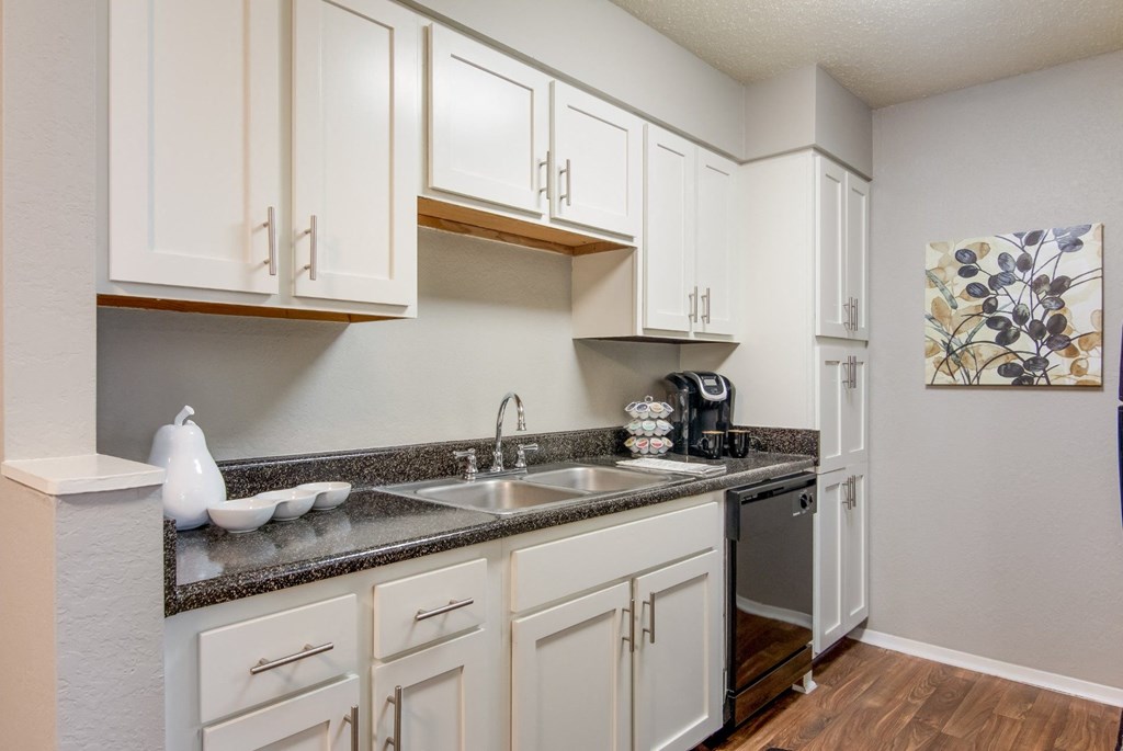 A kitchen with white cabinets and a grey countertop in the model apartment at Stone Canyon apartments in Shreveport, LA.