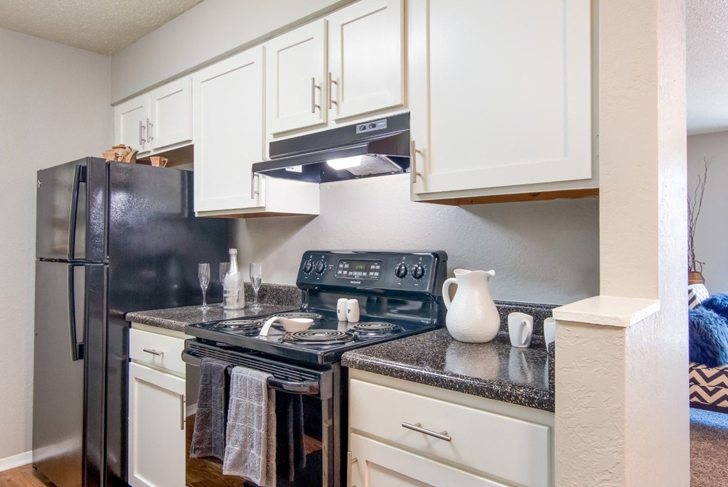 A kitchen with black appliances and white cabinets in the model apartment at Stone Canyon apartments in Shreveport, LA.