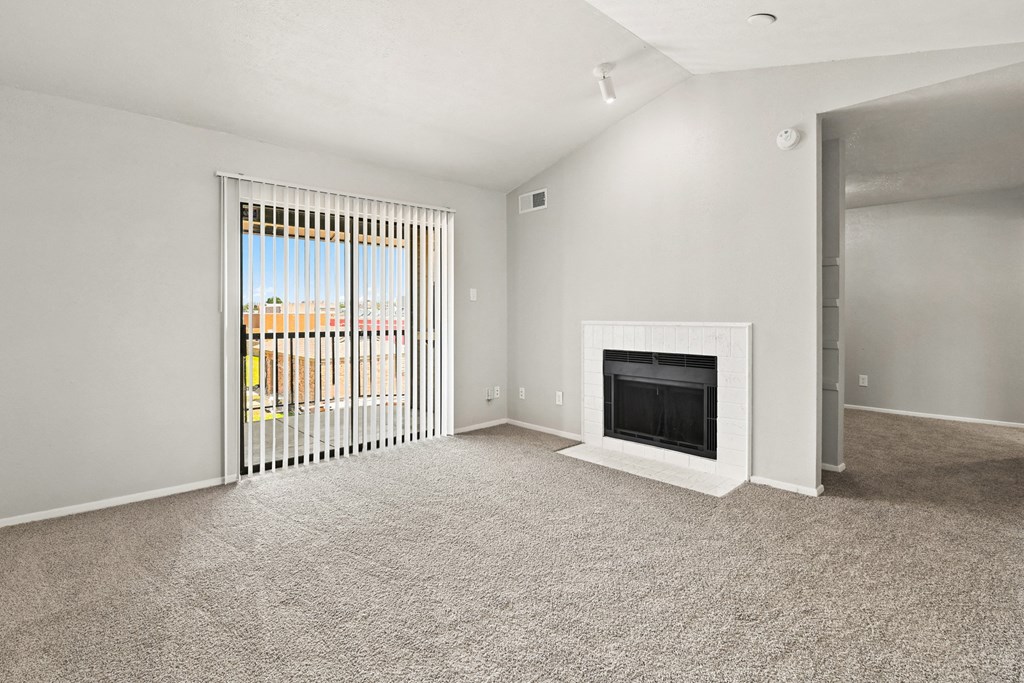 a living room with a fireplace and a door leading to a balcony