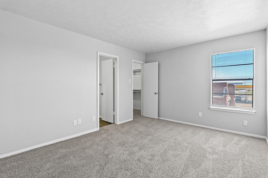 a bedroom with a large window and carpeted flooring