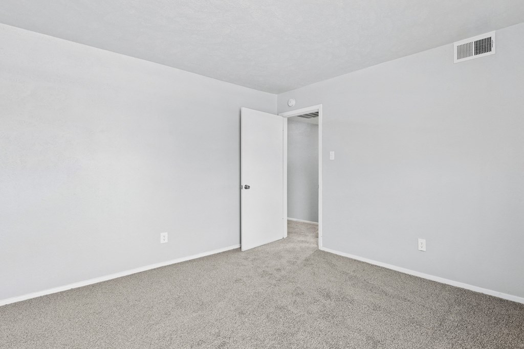 a bedroom with white walls and carpet