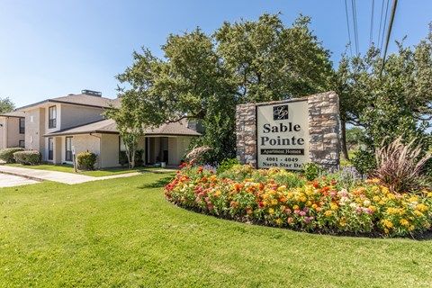 the estates at tanglewood|stone sign and flowers in front of the building