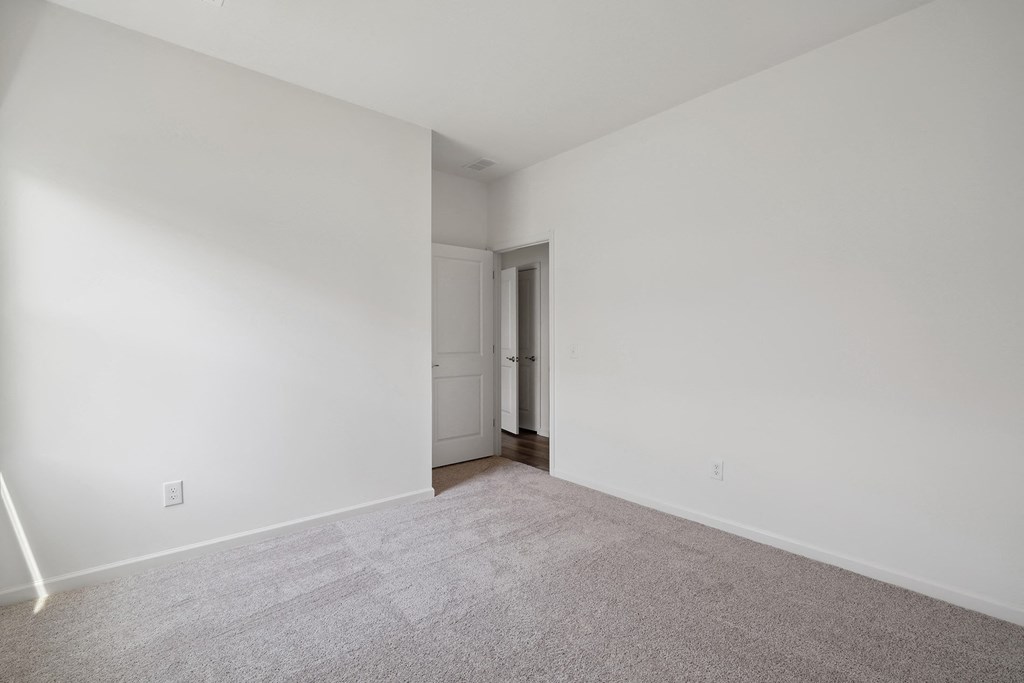 an empty living room with white walls and carpet