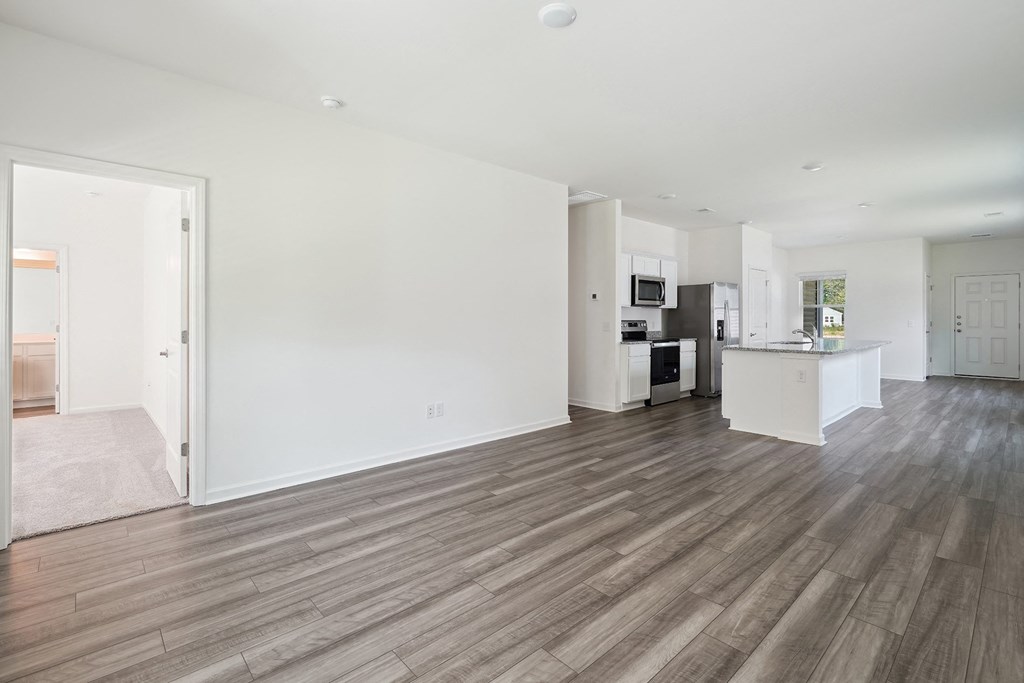 a living room and kitchen with white walls and wood floors
