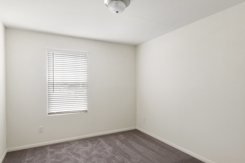 a bedroom with white walls and a window with a white blind