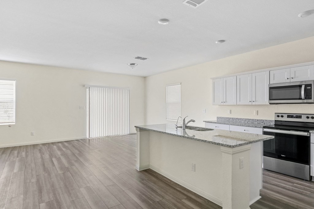 a kitchen and living room with wood floor and white walls
