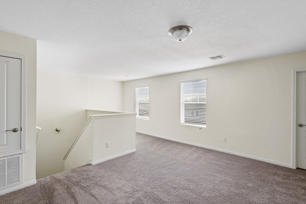 loft room with a staircase, carpeted floor and two windows