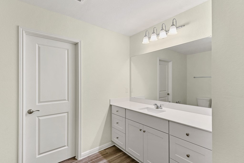 a bathroom with white cabinets, a sink and a mirror