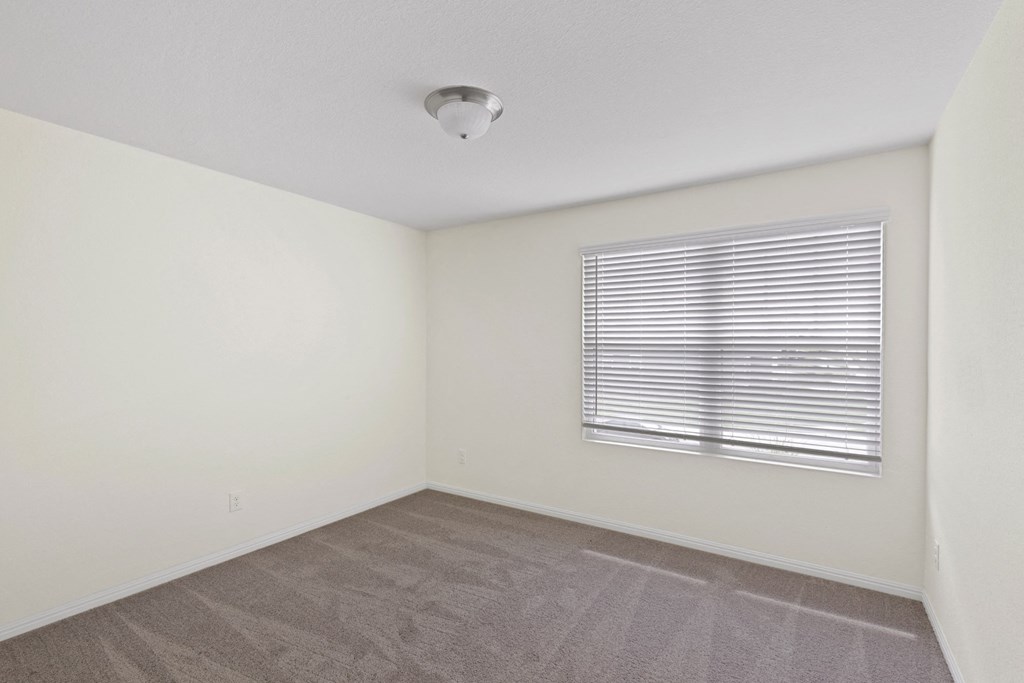 a bedroom with a large window and white walls