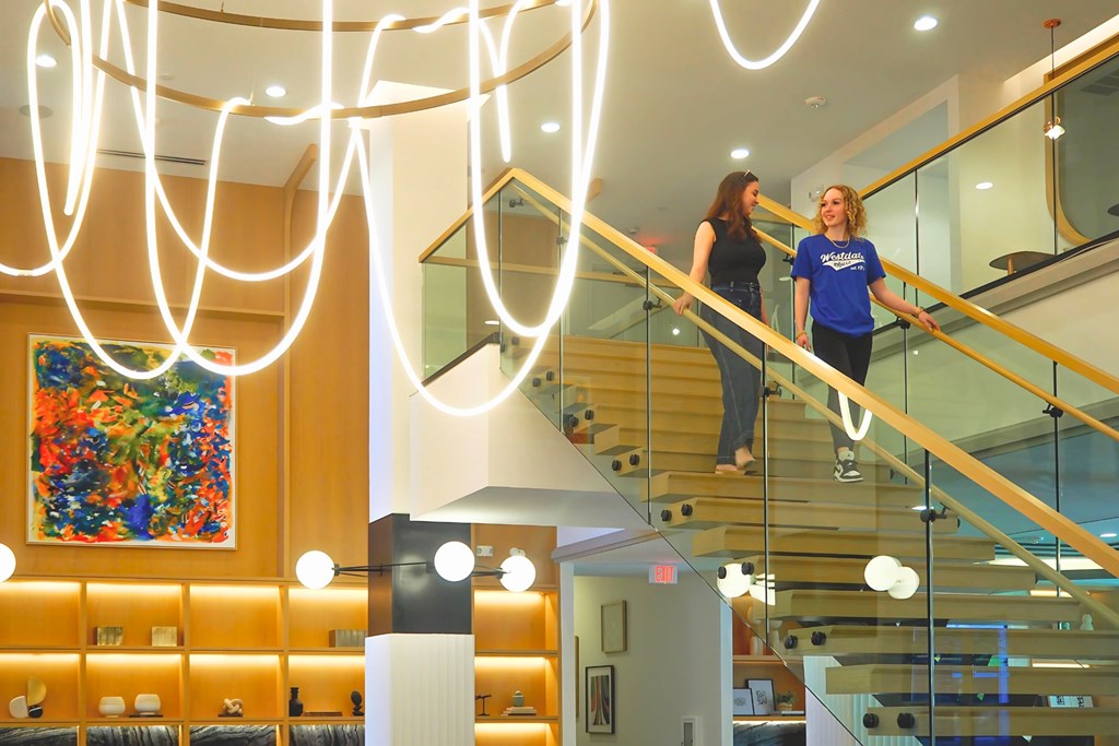 Two women are walking down a staircase at Era Apartments in Denton, TX
