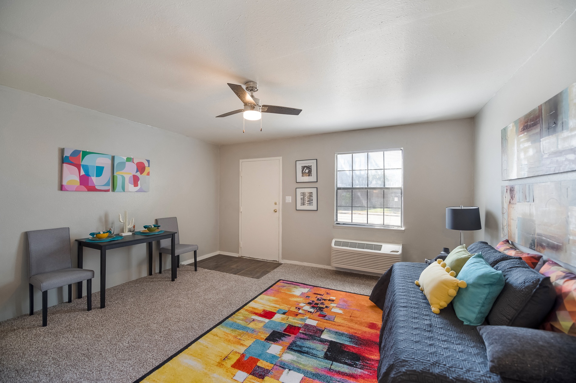 a living room with a couch and a desk and a ceiling fan