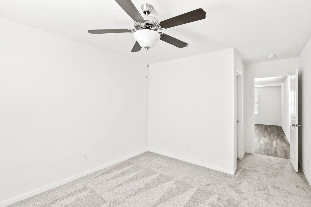 a bedroom with carpet floor, white walls and a ceiling fan