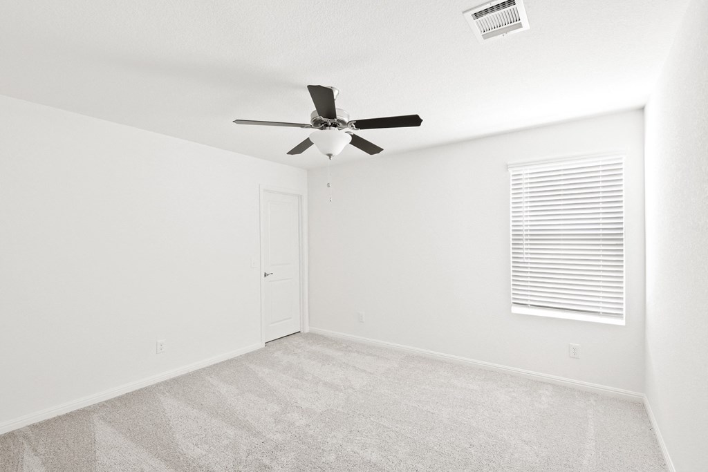 a bedroom with a window, white walls and a ceiling fan
