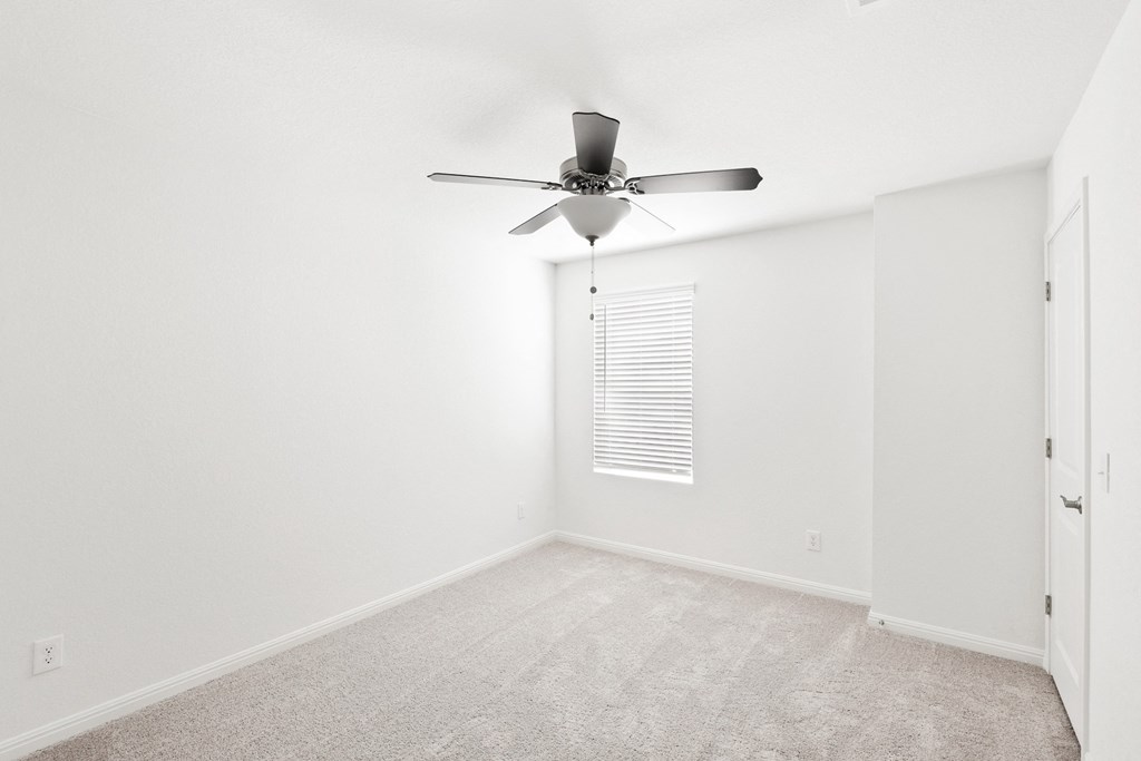 a bedroom with white walls and a ceiling fan