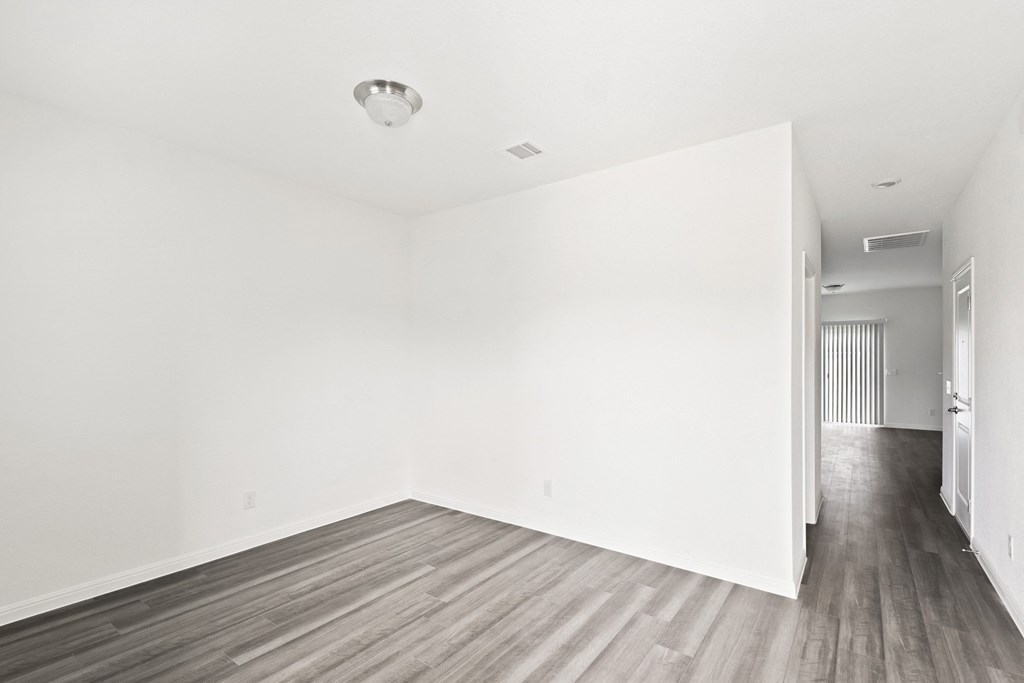 a bedroom with hardwood floors and white walls