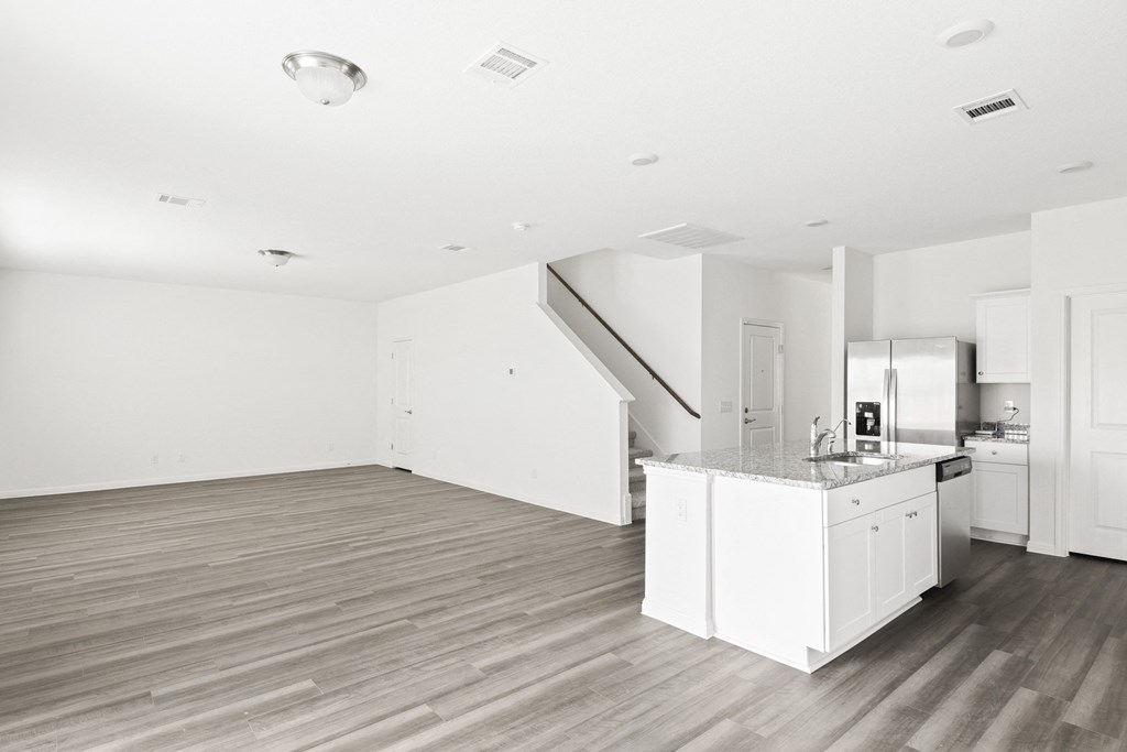a kitchen and living room with white walls and wood floors