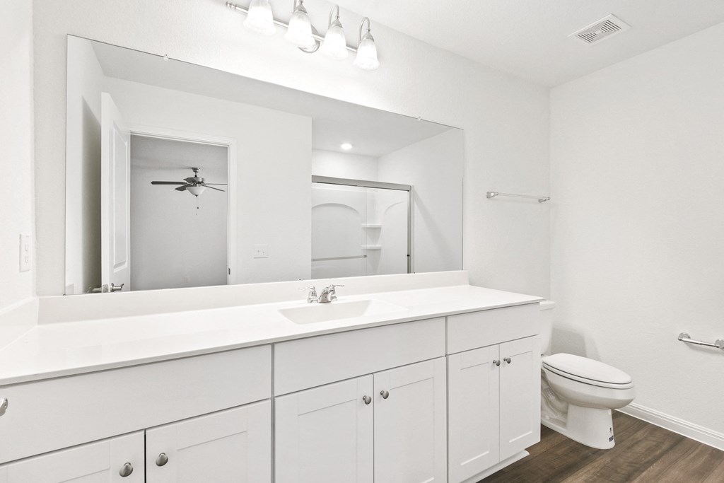 master bathroom with a large mirror and white cabnites