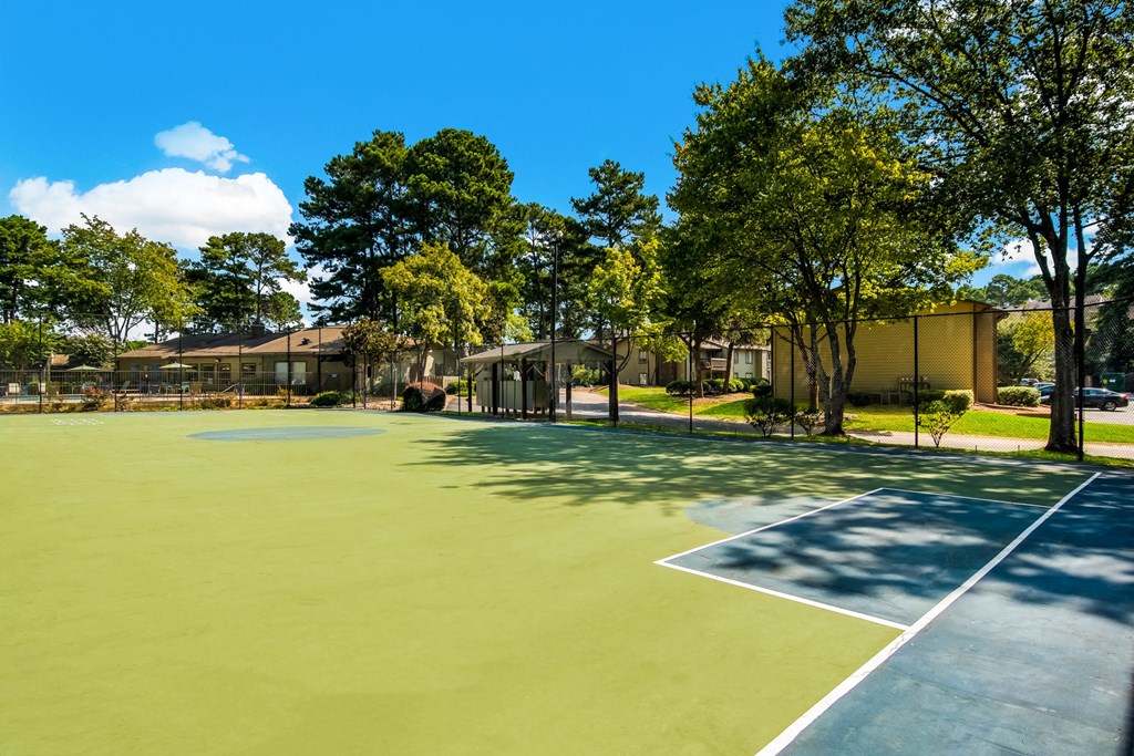 a tennis court with trees and a building in the background