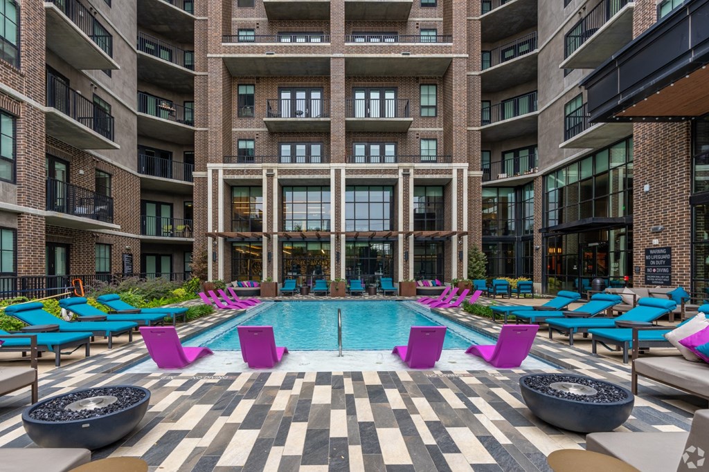 Our sparkling pool with blue loungers and pink in-pool lounge chairs at The Case apartments in Dallas, TX