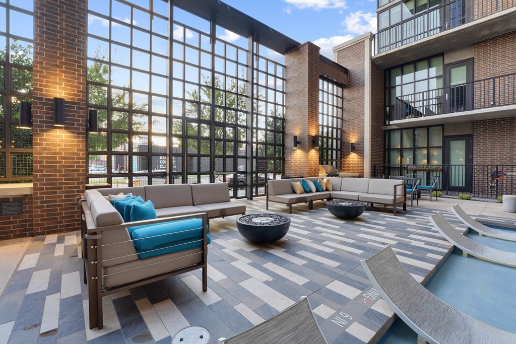 a lounge area with couches chairs and a fire pit in front of a large window at The Case Building in Dallas, TX
