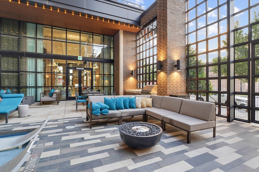 a lounge area with couches and chairs in front of a building with large windows at The Case Building in Dallas, TX