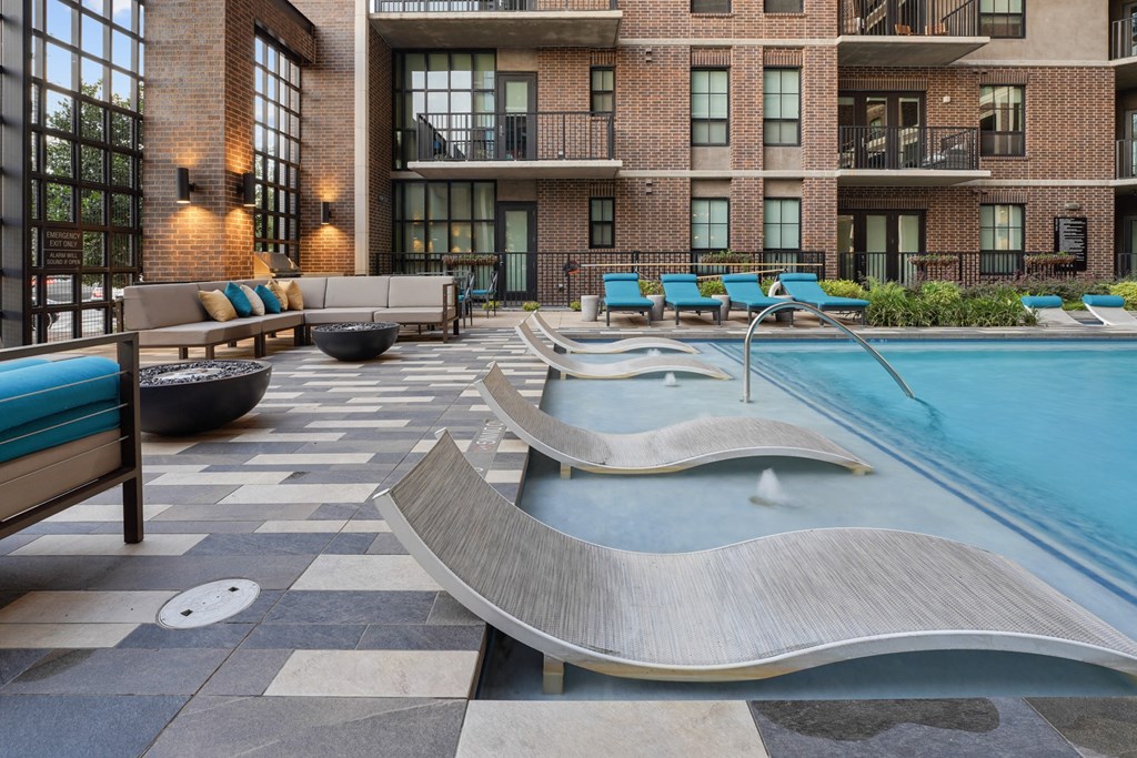 a pool with lounge chairs and a fire pit at The Case Building in Dallas, TX