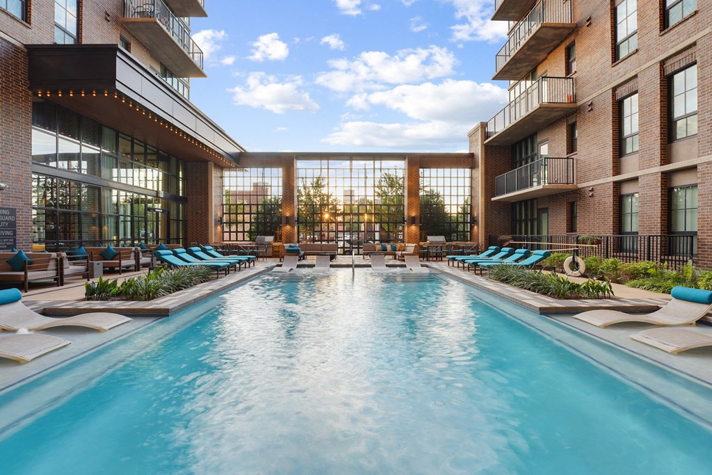 a pool with blue chaise lounge chairs at The Case Building in Dallas, TX