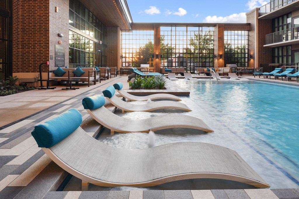 a pool with chaise lounge chairs and a brick building in the background at The Case Building in Dallas, TX