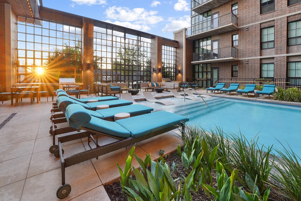 a pool with blue chaise lounge chairs at The Case Building in Dallas, TX