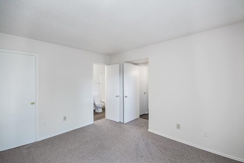 A white room with a carpeted floor and two open doors.