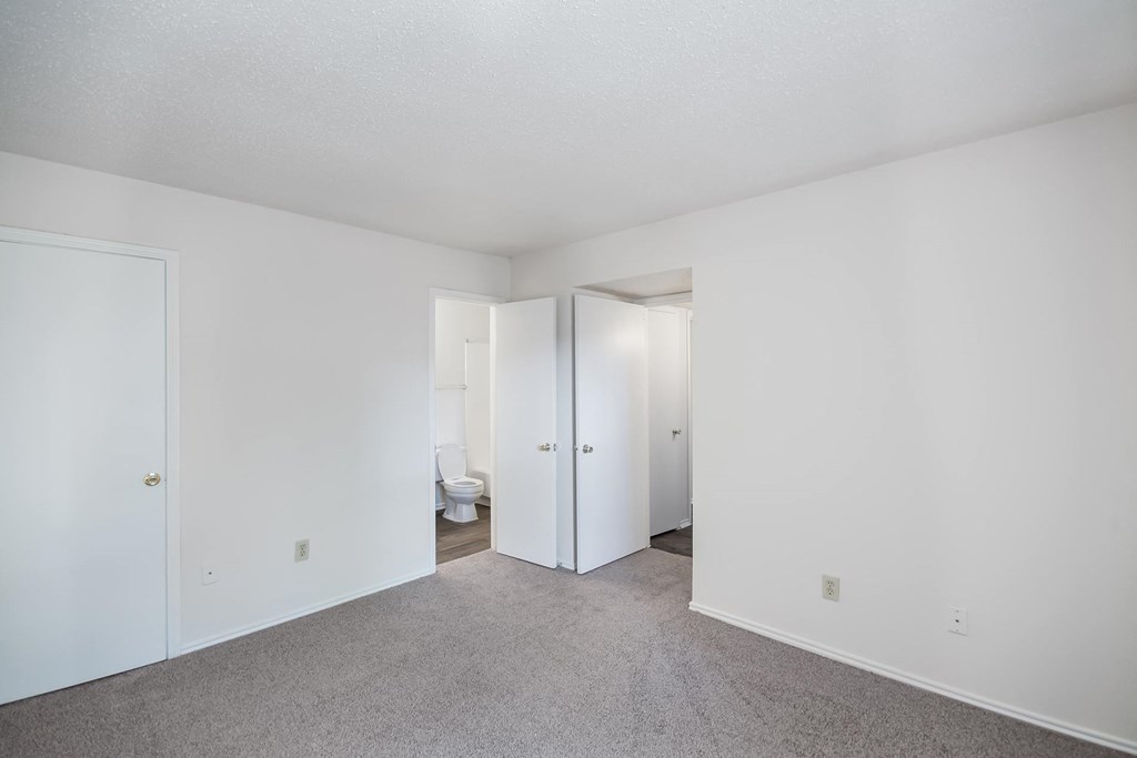 an empty living room with white walls and a bathroom