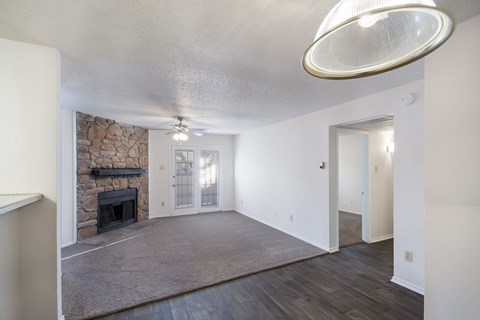 A spacious living room with a stone fireplace and a grey rug.