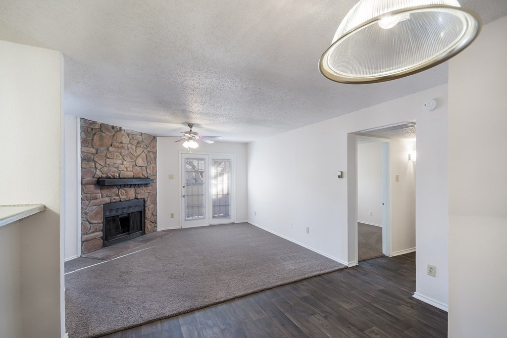 an empty living room with a fireplace and a ceiling fan