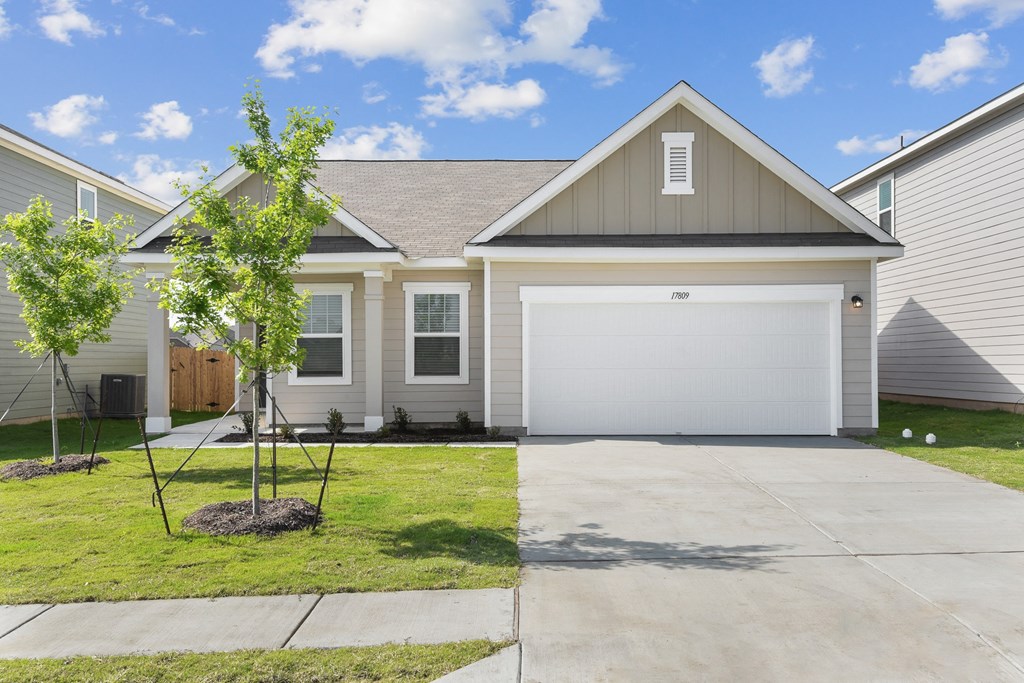 a house with a tree in the front yard at Beacon at Vine Creek, Pflugerville, TX