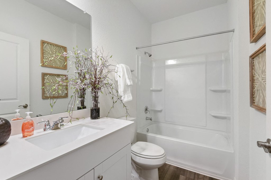 a bathroom with a white sink and toilet next to a white bathtub with a shower curtain  at Beacon at Vine Creek, Pflugerville, TX, 78660