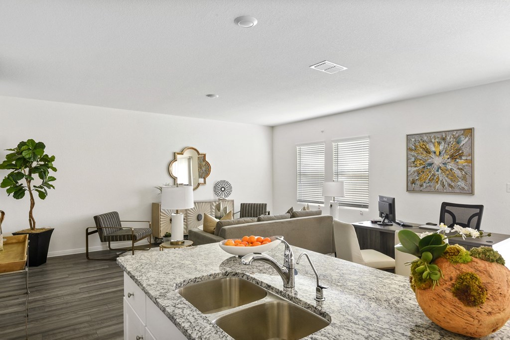a kitchen with a sink and a counter top next to a living room with a couch and  at Beacon at Vine Creek, Pflugerville, TX, 78660